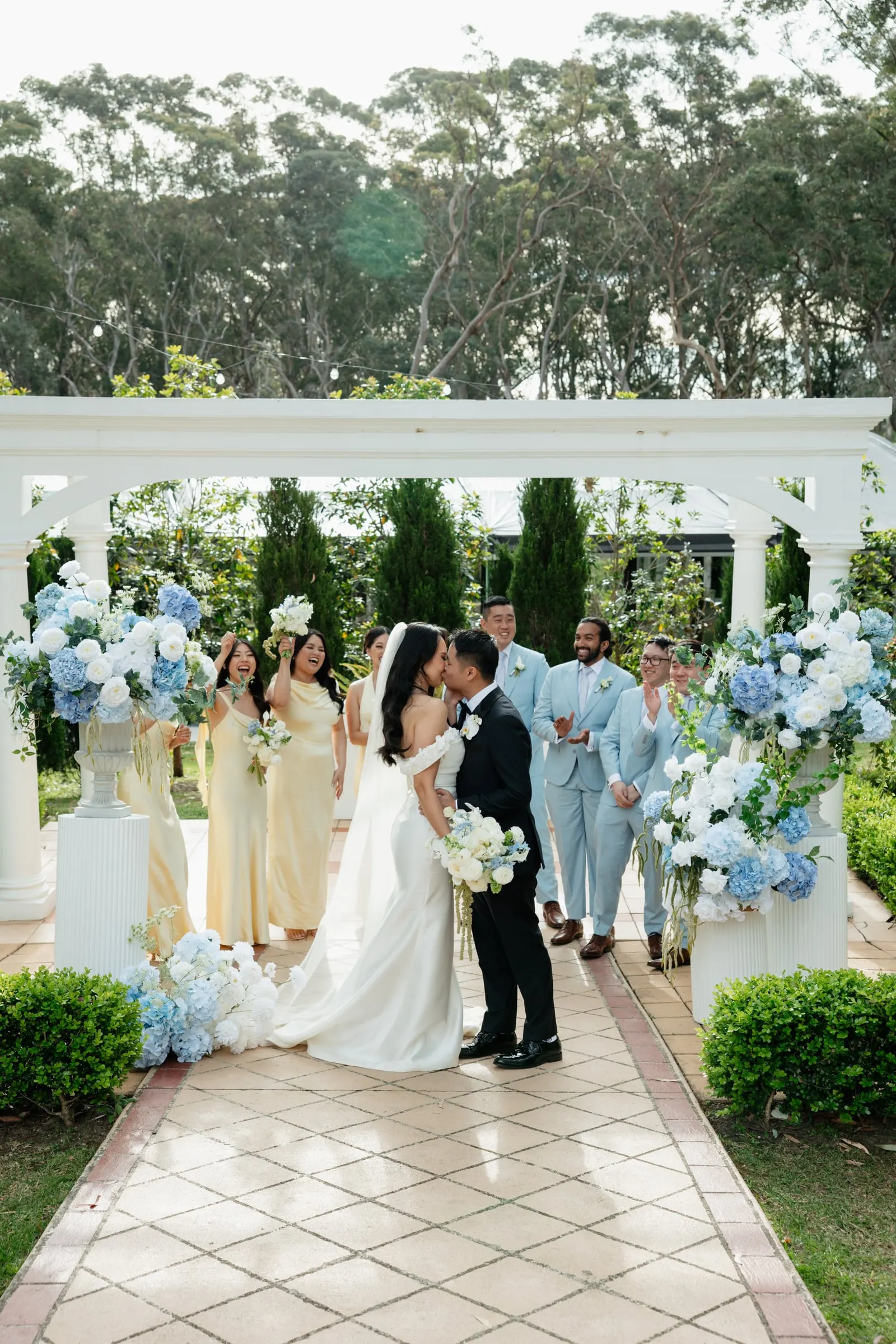 Newlyweds walking back down an aisle lined with blue and white hydrangeas