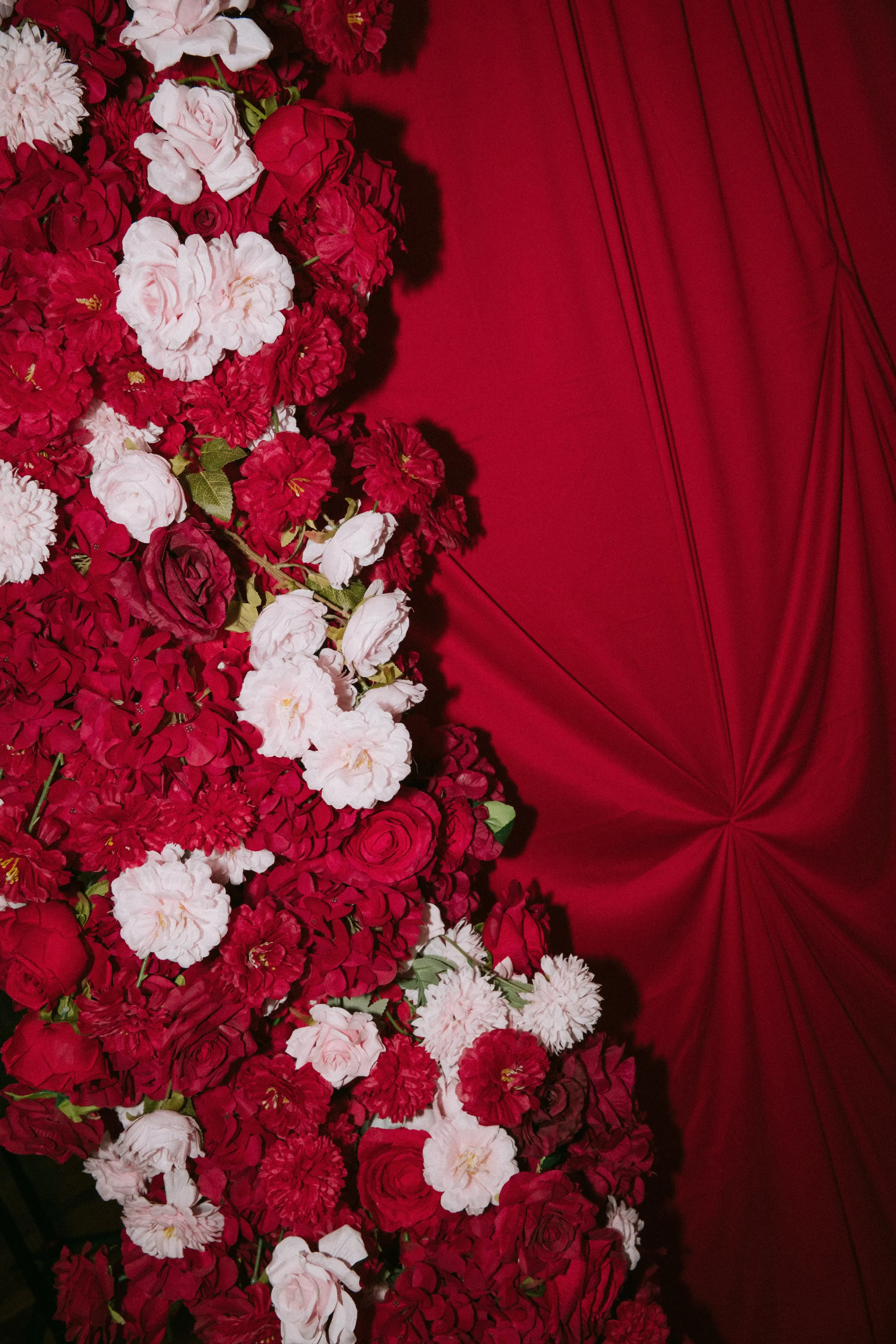 Cascade of red and white roses against a gathered red drape for a tea ceremony