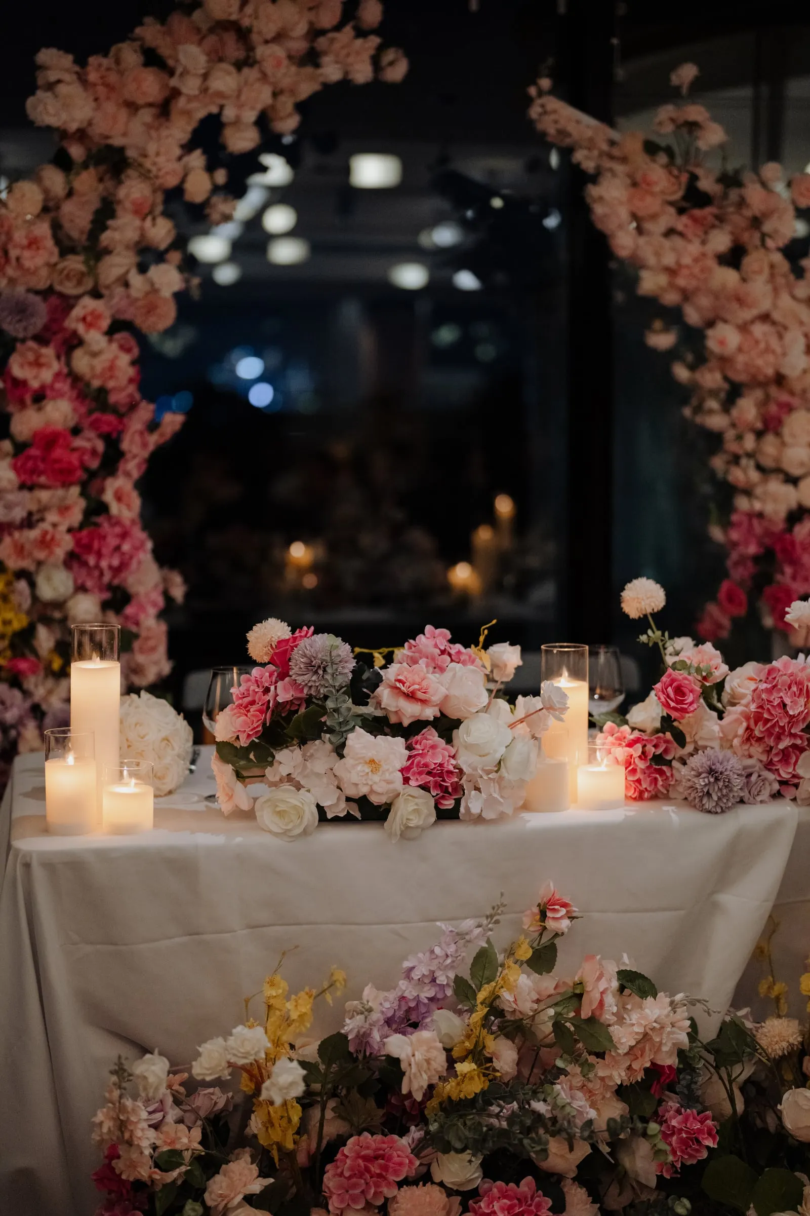 Round mirror backdrop surrounded by pink and white florals and candles behind the bridal table